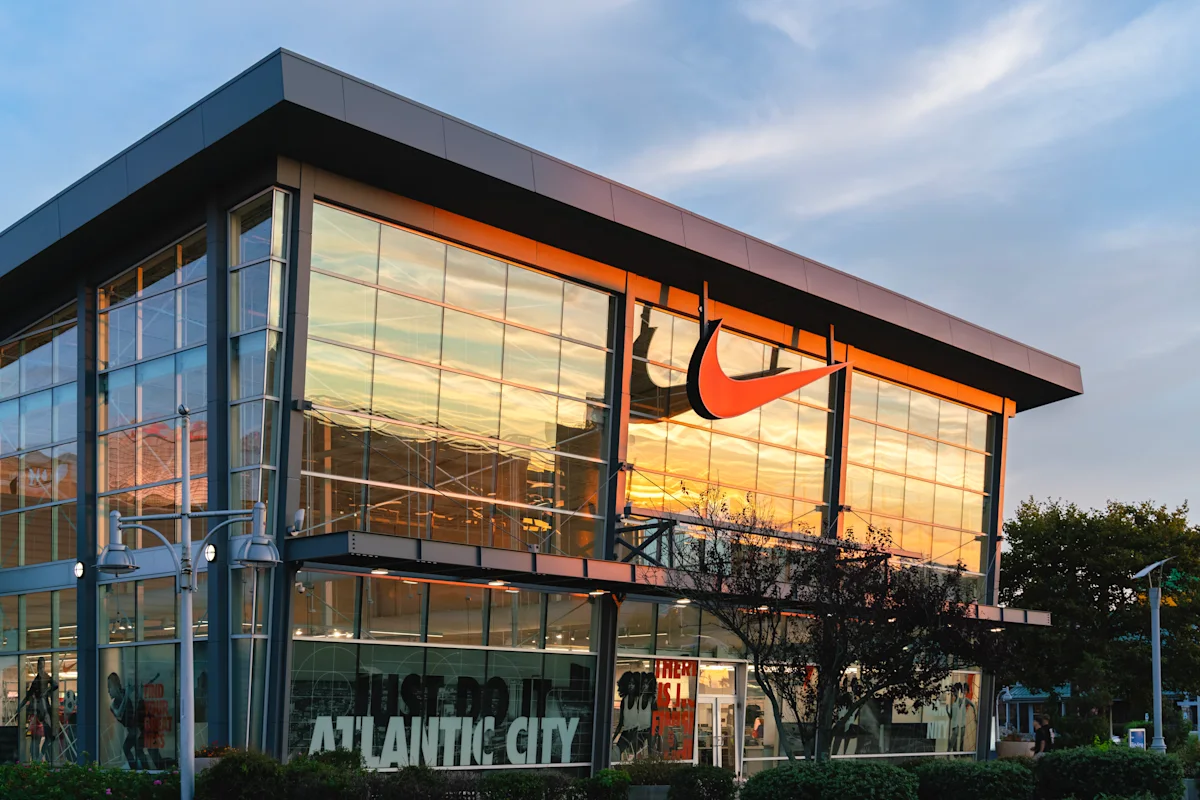 Grafik penurunan saham Nike dan logo perusahaan di pasar modal Wall Street