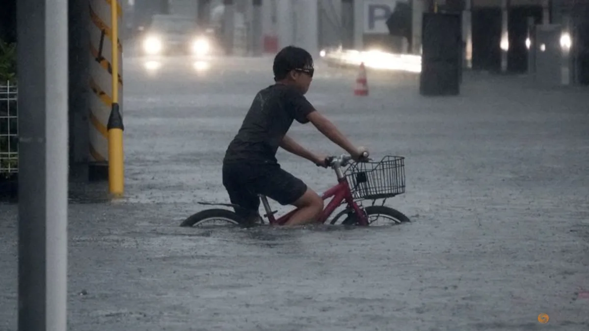 Seorang anak mengendarai sepeda di jalan yang terendam banjir akibat Topan Dujuan di Jepang